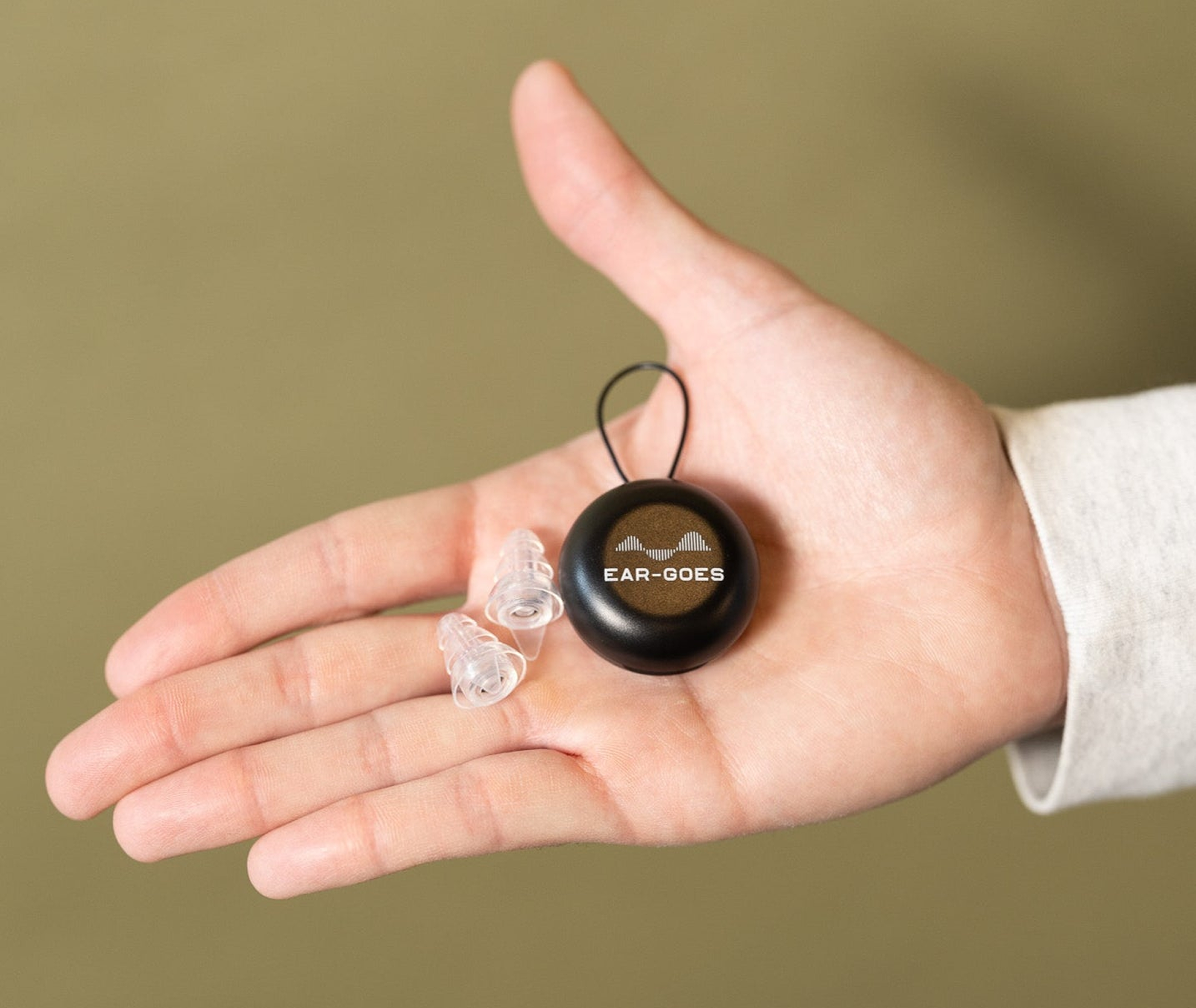 A person holding Ear-Goes high fidelity silicone earplugs and clamshell case in their hand.